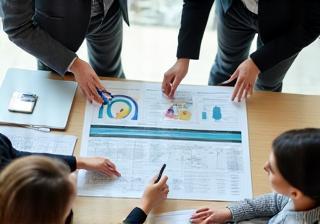 Consultants discussing a strategic plan or map laid out on a table.